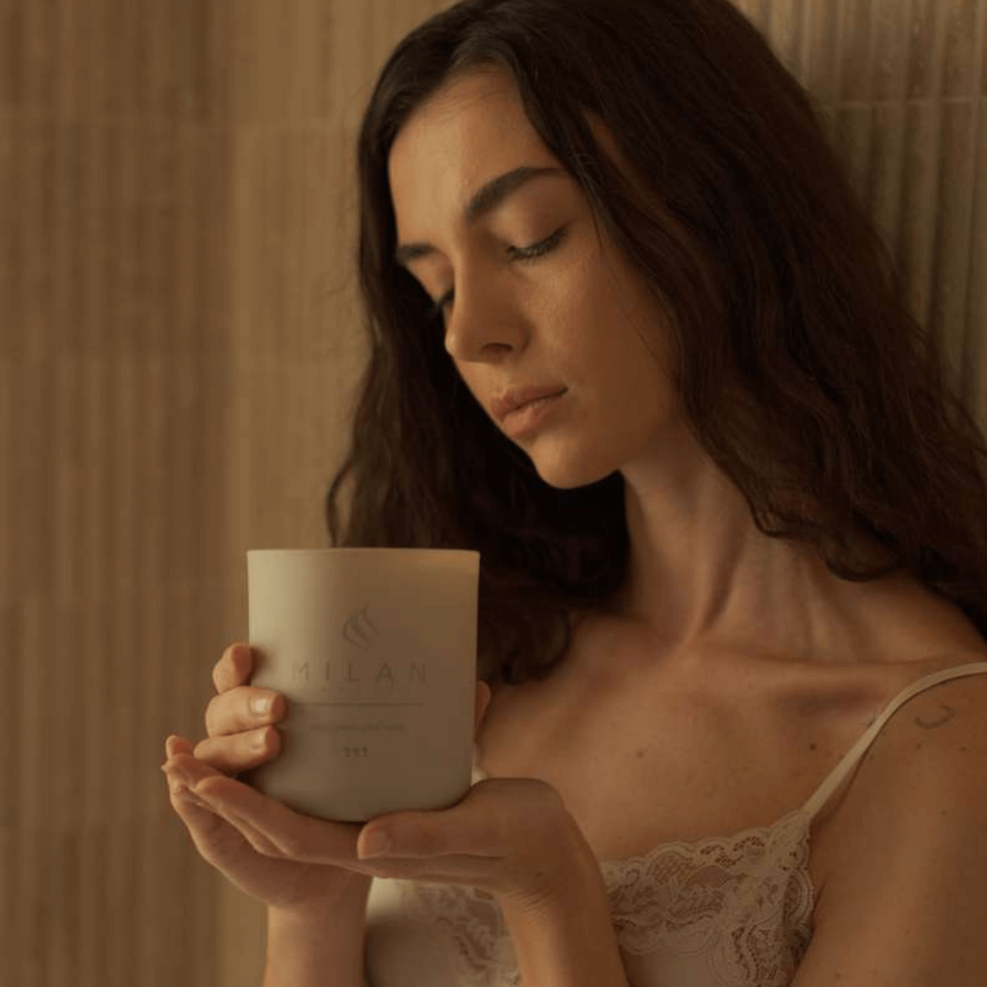 Woman holding a Milan candle with a warm glow against a neutral background