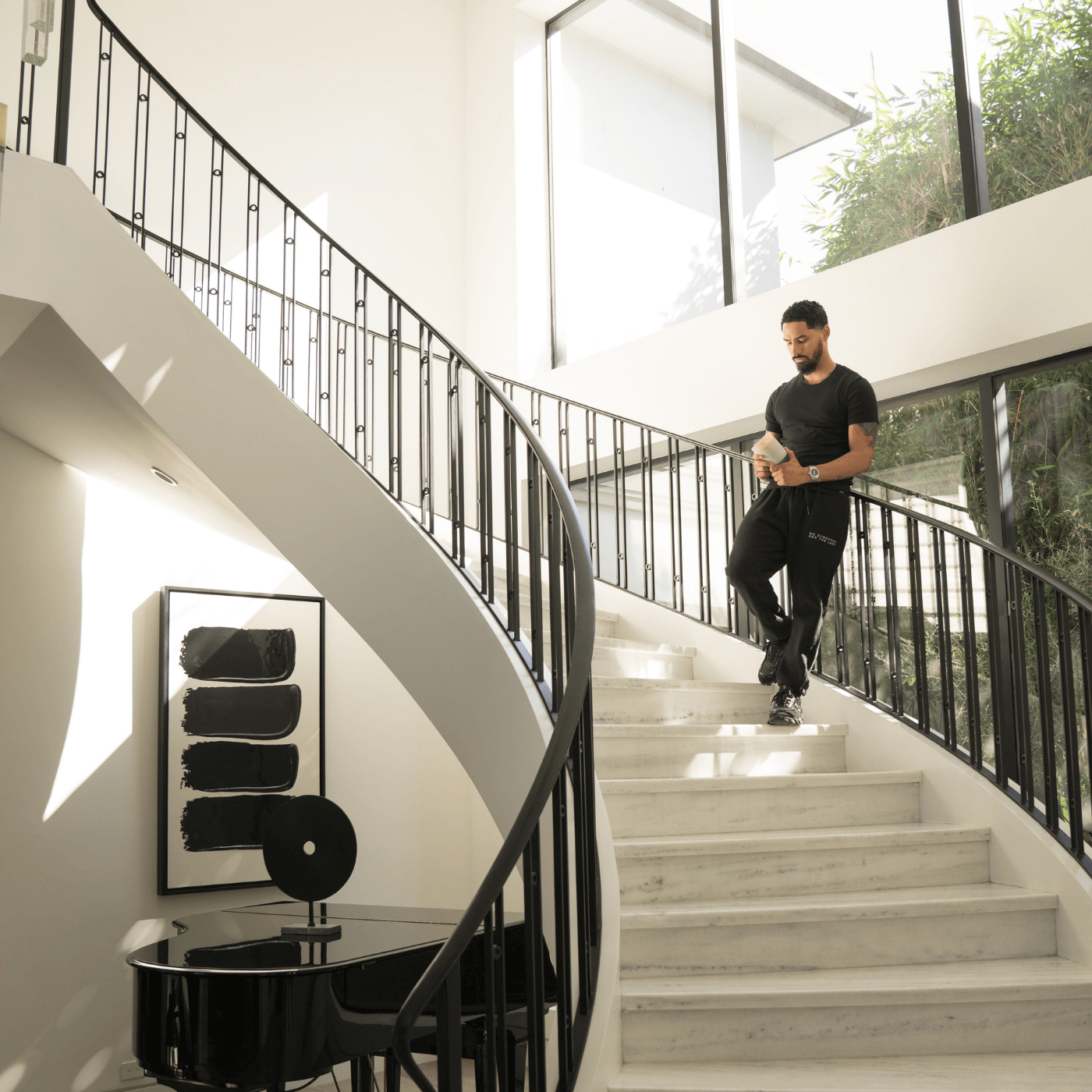 The CEO of Milan Candles, Luis Garcia,  standing on a modern staircase holding a Milan Candle.
