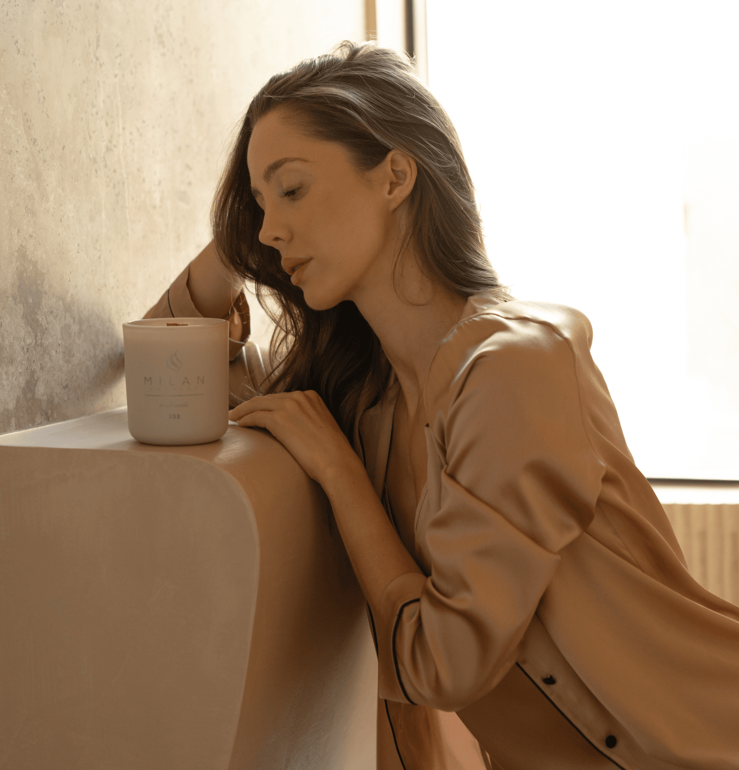 Woman leaning on a table with a Milan candle, soft natural light